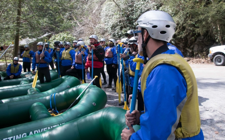 a group of people stand around empty rafts on an outward bound expedition 
